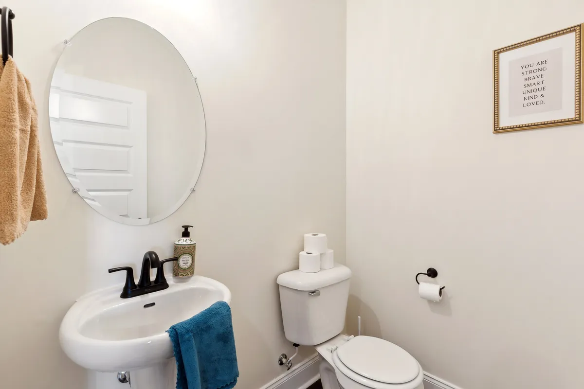 A stylish bathroom vignette focused on a large round mirror, a contemporary sink, and an inspirational quote framed on the wall. The atmosphere is inviting and uplifting, ideal for daily routines.