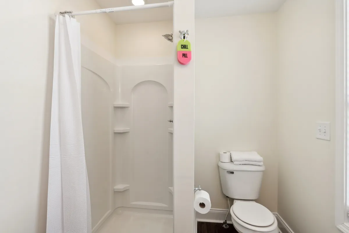 A sleek bathroom with a modern shower area, fresh towels, and a toilet. The space is spotless, with calm lighting and a serene, spa-like atmosphere.