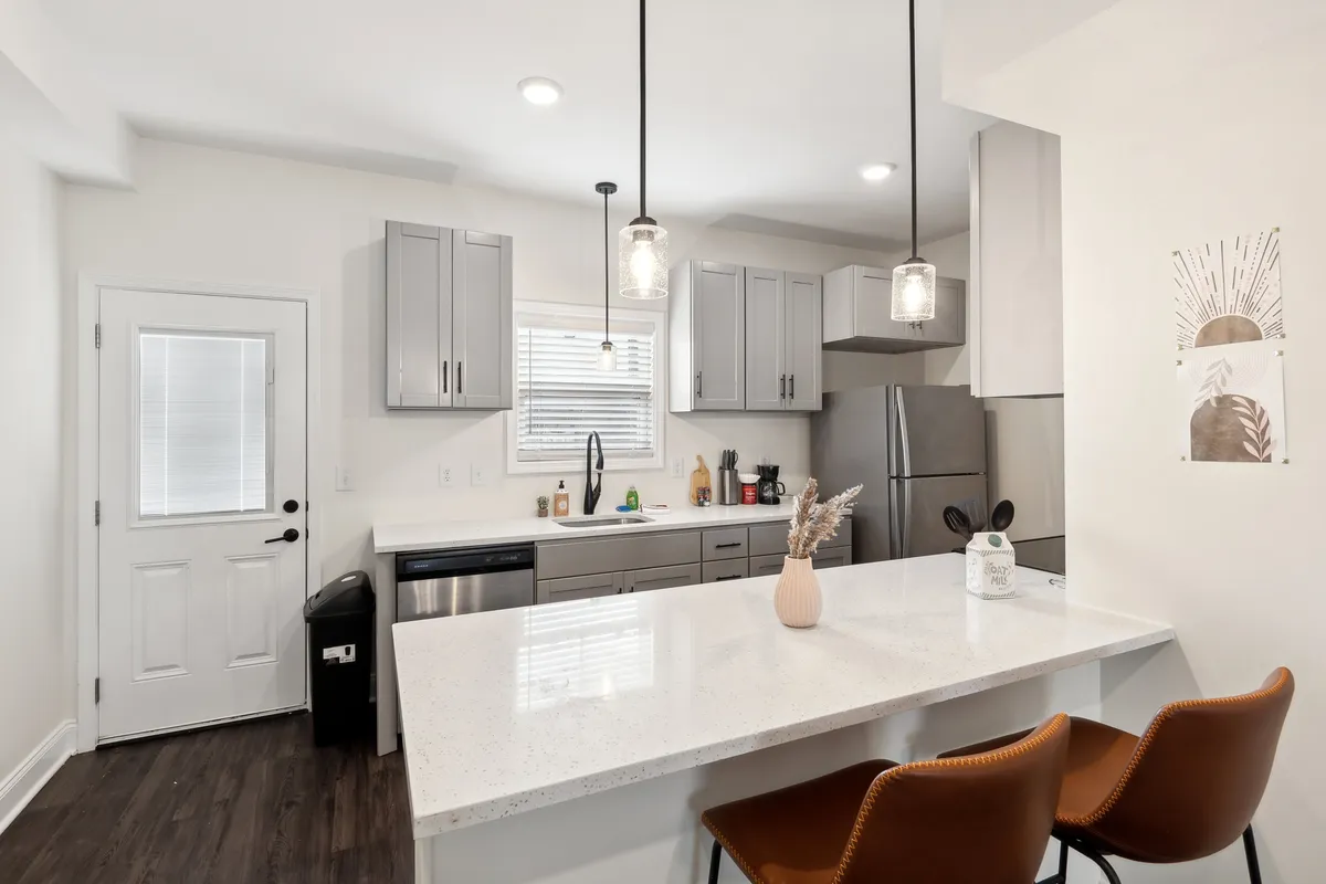 A spacious, contemporary kitchen featuring a large island with bar stools, sleek stainless steel appliances, and pendant lighting. The space is open and inviting, with ample room for cooking, entertaining, and casual dining.